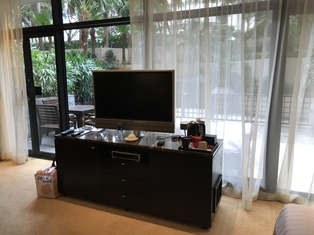 a tv on a desk in a room with a glass wall and plants