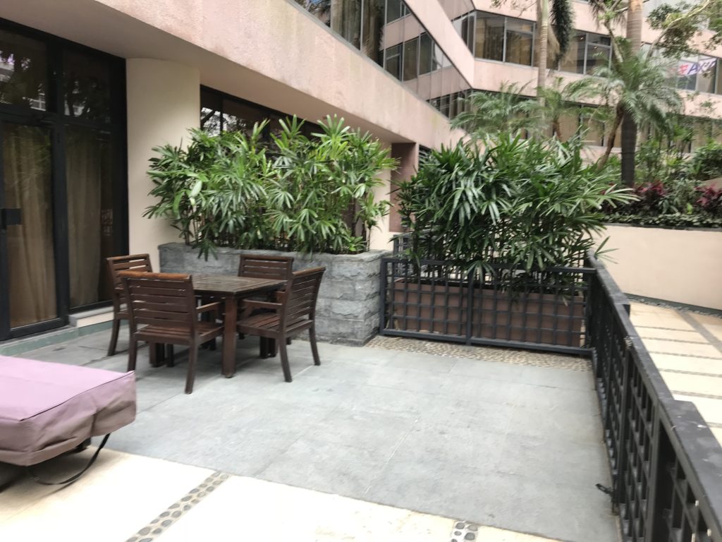 a patio with a table and chairs and plants