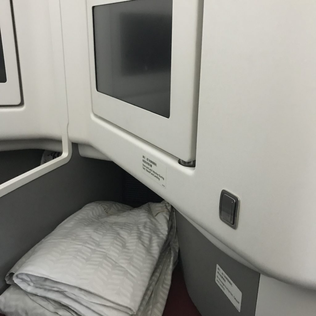 a white bed and a white pillow on a plane