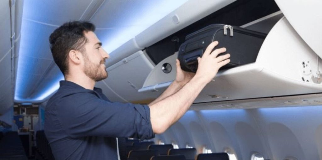 a man holding a suitcase on an airplane