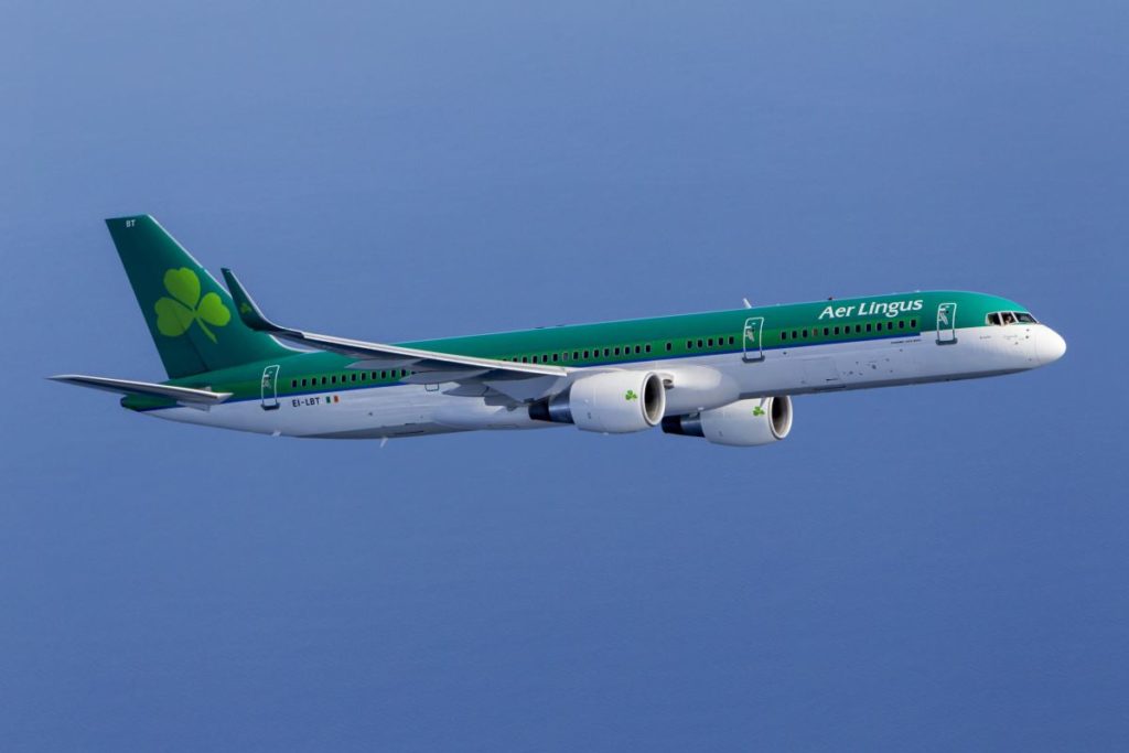 a green and white airplane flying in the sky