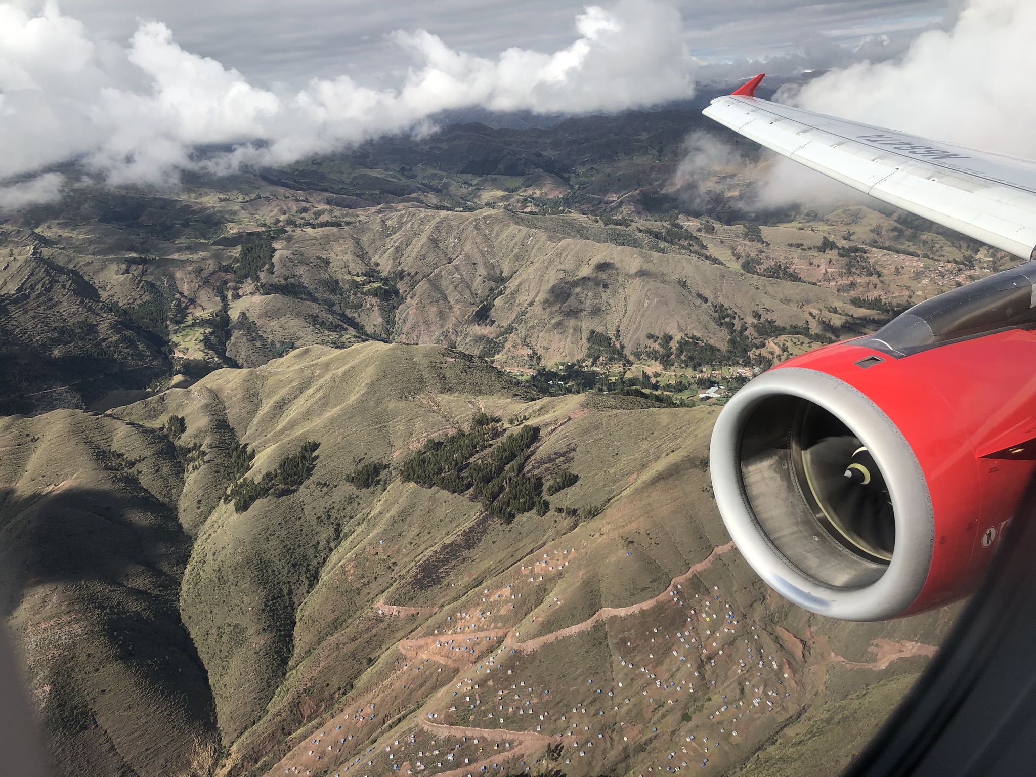 an airplane wing and engine of a plane flying over mountains