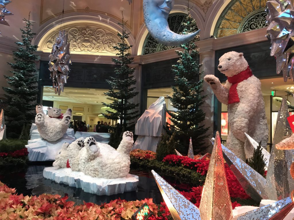 a large white bear statue in a room with trees and flowers