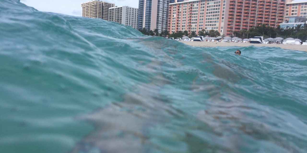 a wave of water with buildings in the background