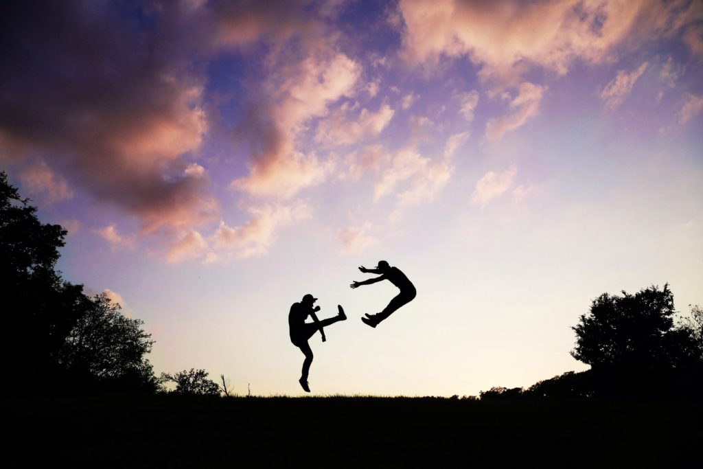 a silhouette of a man kicking another man