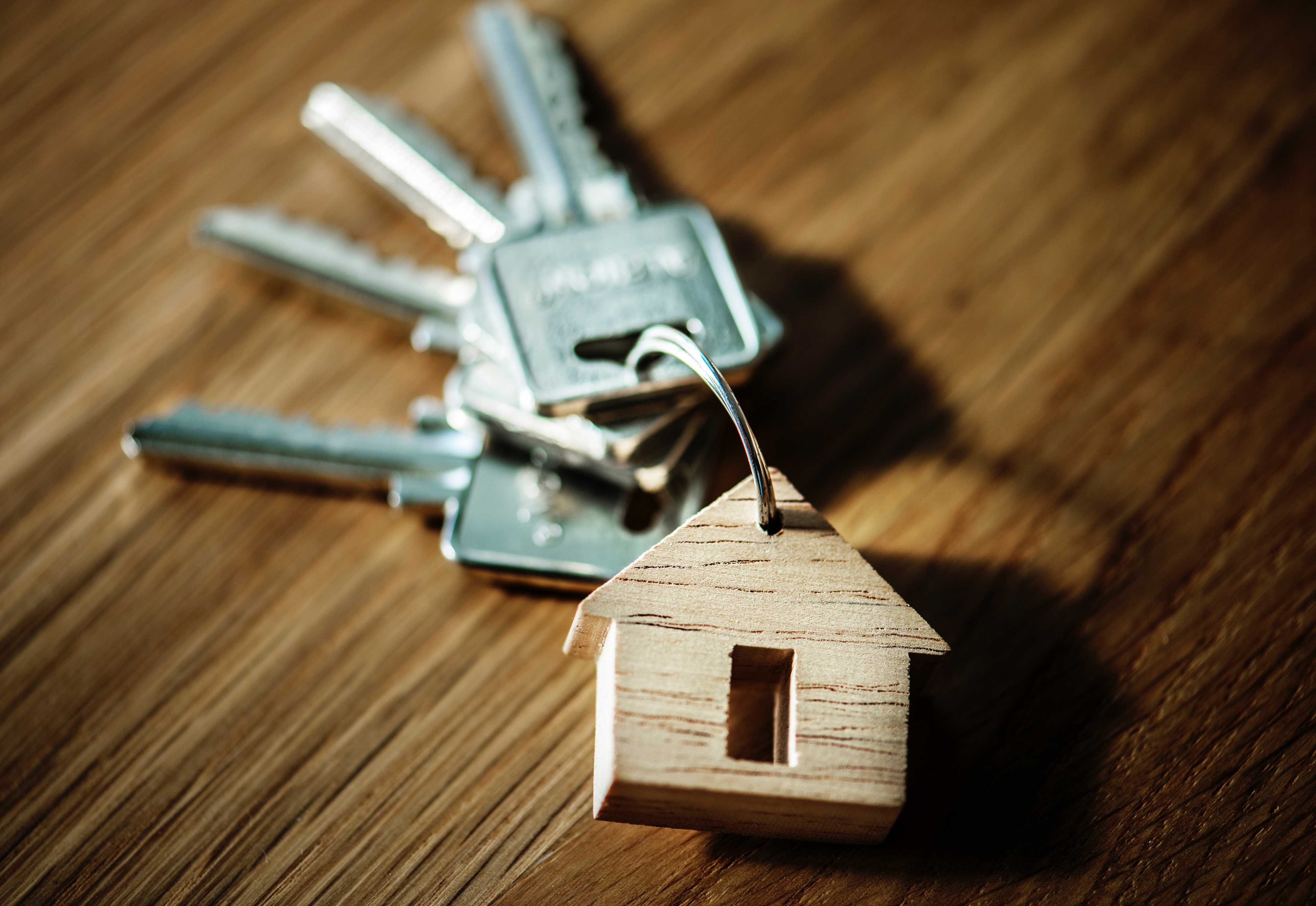 a wooden house keychain with keys on a wood surface