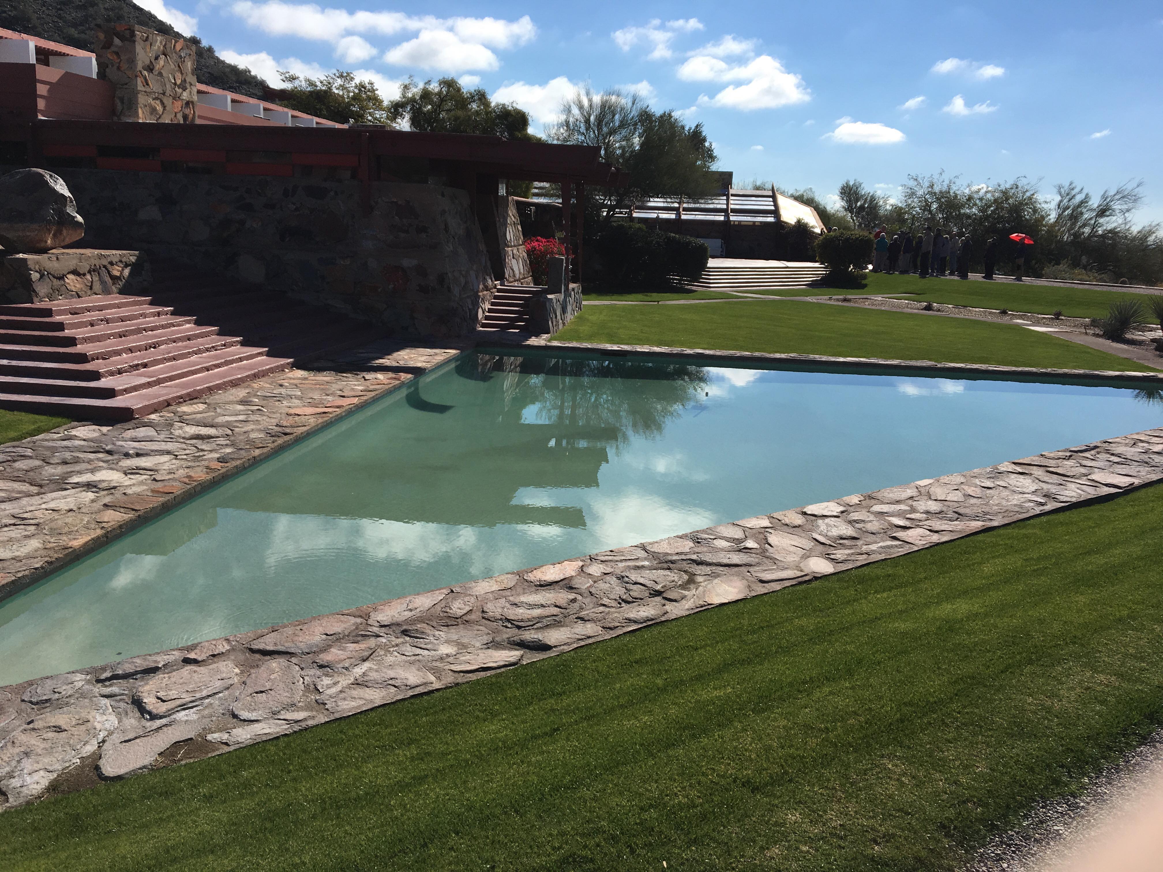 a pool with grass and a stone wall