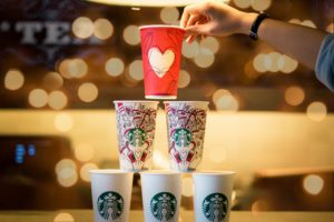 a hand holding a red cup over a stack of cups