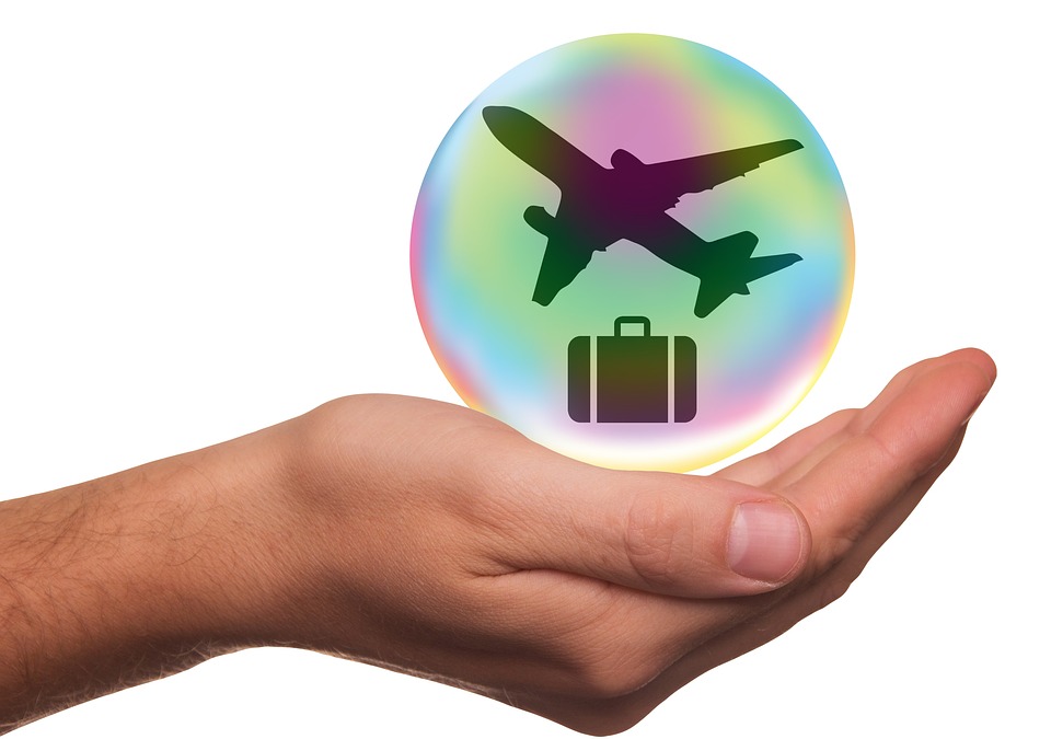 a hand holding a bubble with a plane and suitcase