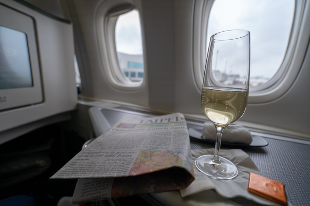 a glass of wine on a tray with a newspaper and a paper on the table