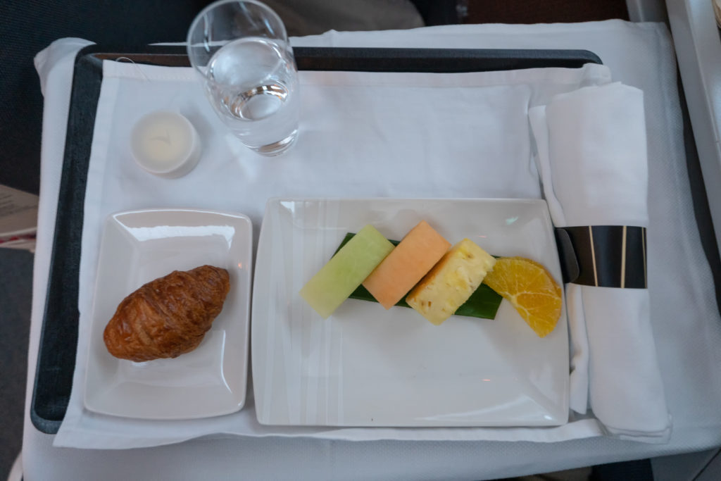 a plate of fruit and croissant on a tray