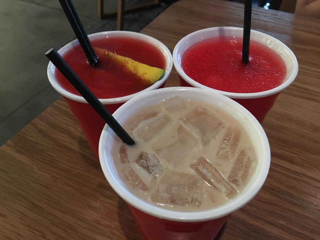 a group of red cups with straws and a fruit in them