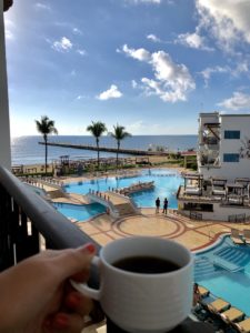 a person holding a cup of coffee overlooking a pool