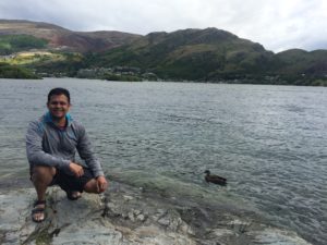 a man sitting on a rock next to a body of water