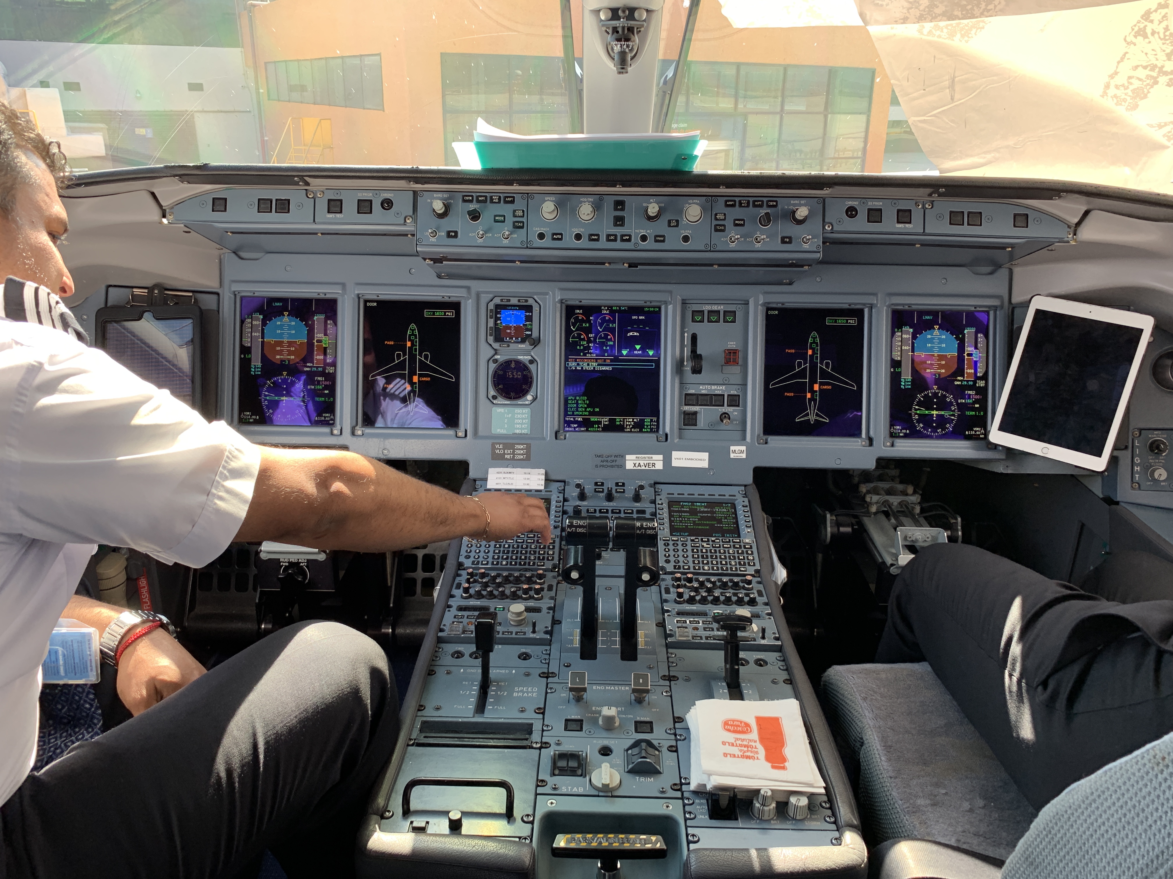 a man in a white shirt and black pants sitting in a cockpit of an airplane