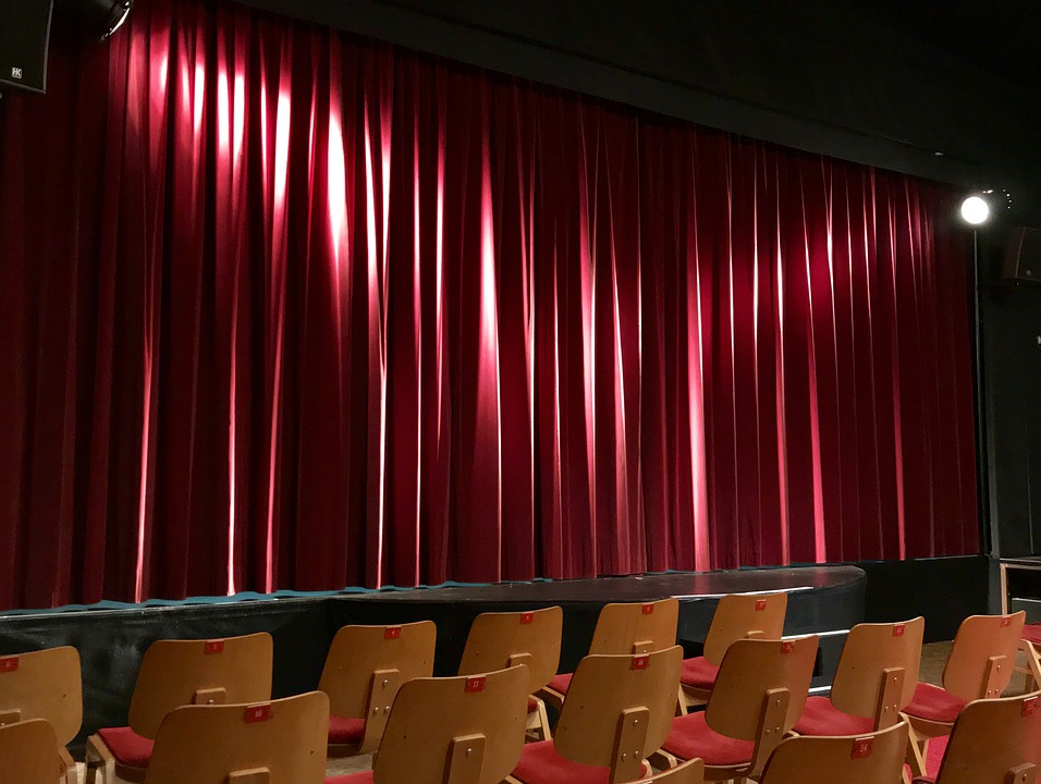 a stage with red curtains and chairs