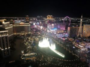 a city at night with a fountain and a ferris wheel