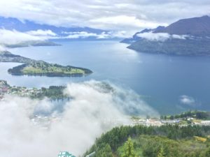 a body of water with clouds and mountains in the background