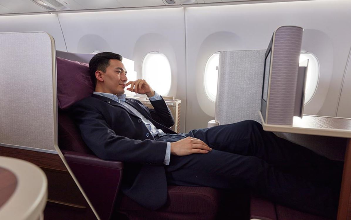 a man in a suit lying on a chair in an airplane