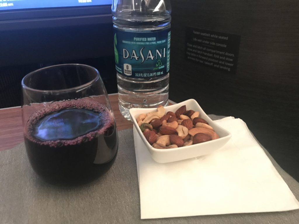 a bowl of nuts and a glass of liquid next to a bottle of water
