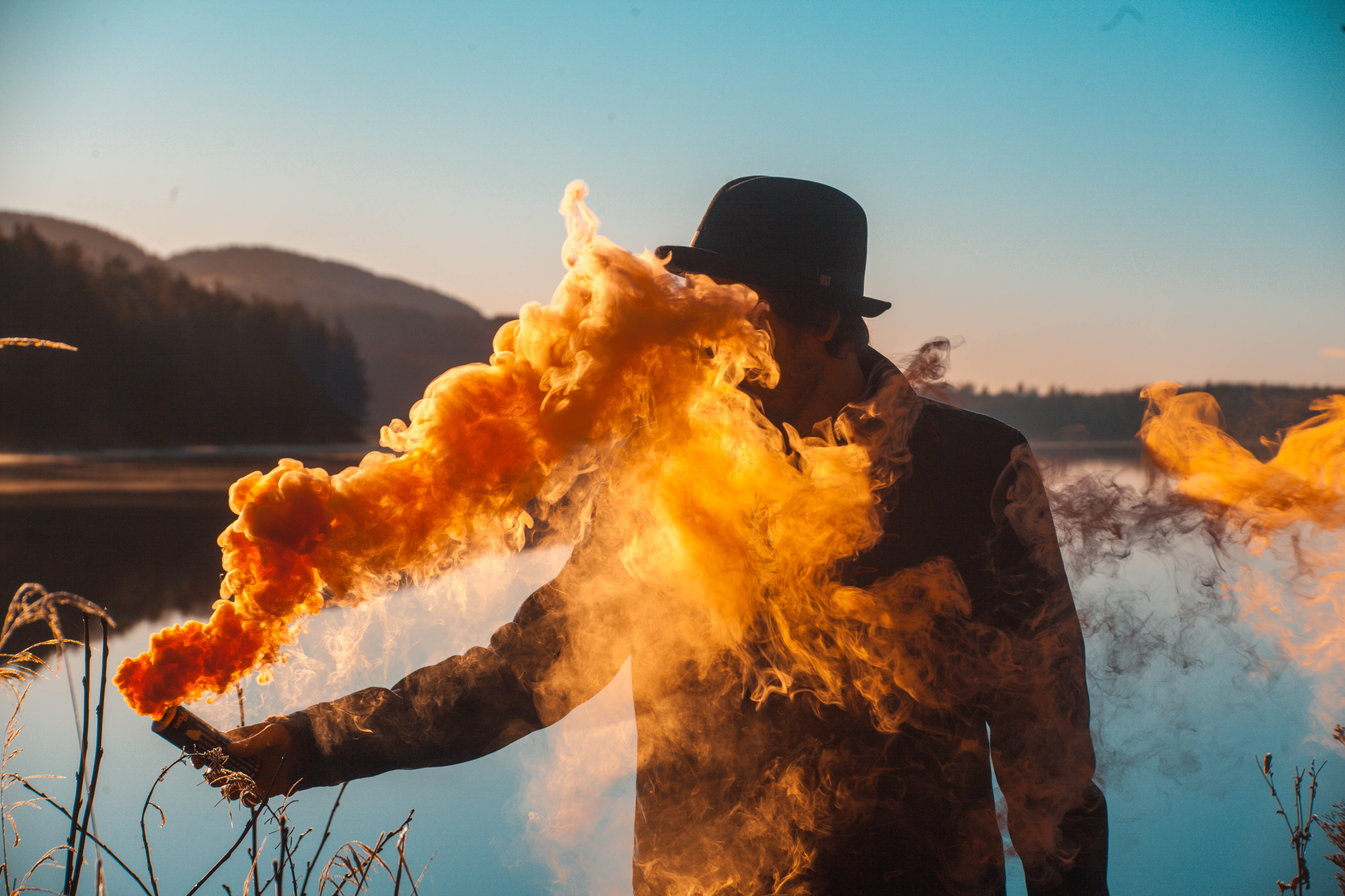 a man in a hat holding an orange smoke bomb