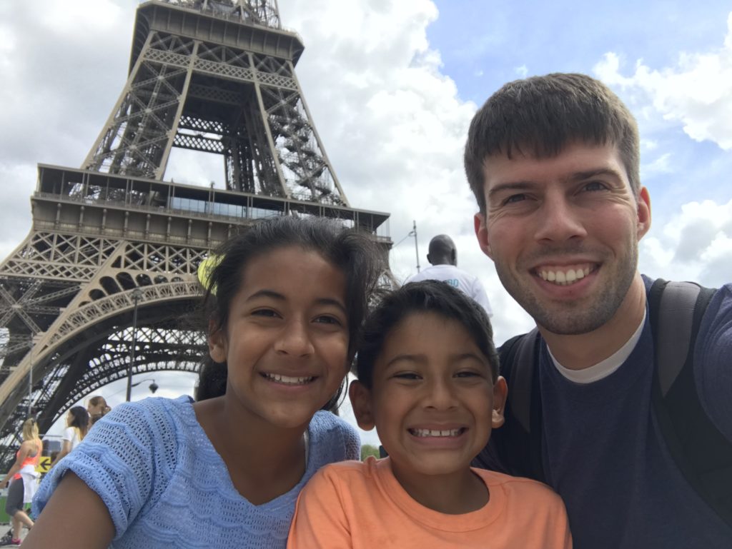 a man and two children posing for a selfie in front of a tower