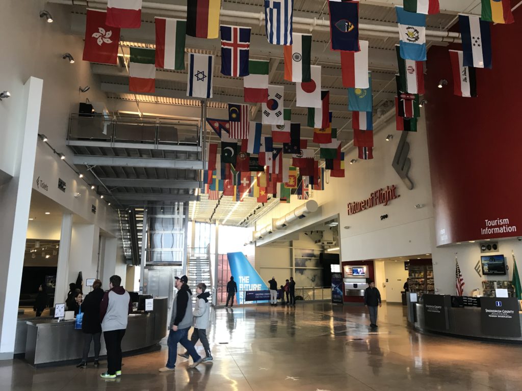 a group of people in a building with flags from the ceiling