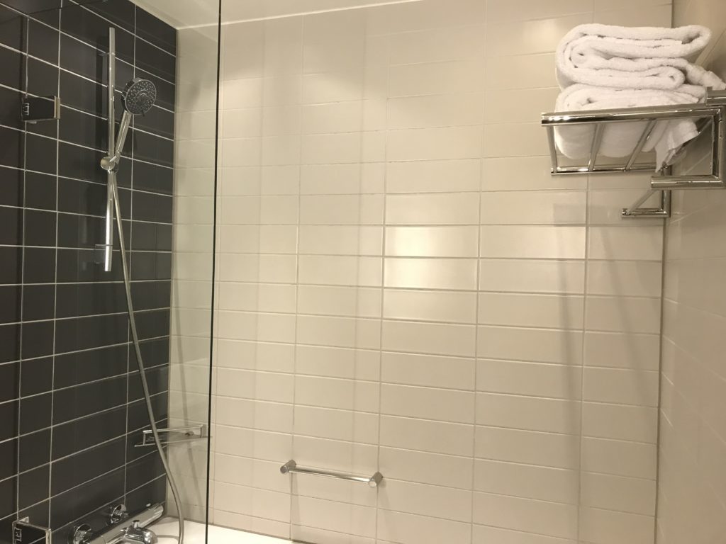 a shower with a shower head and a towel rack