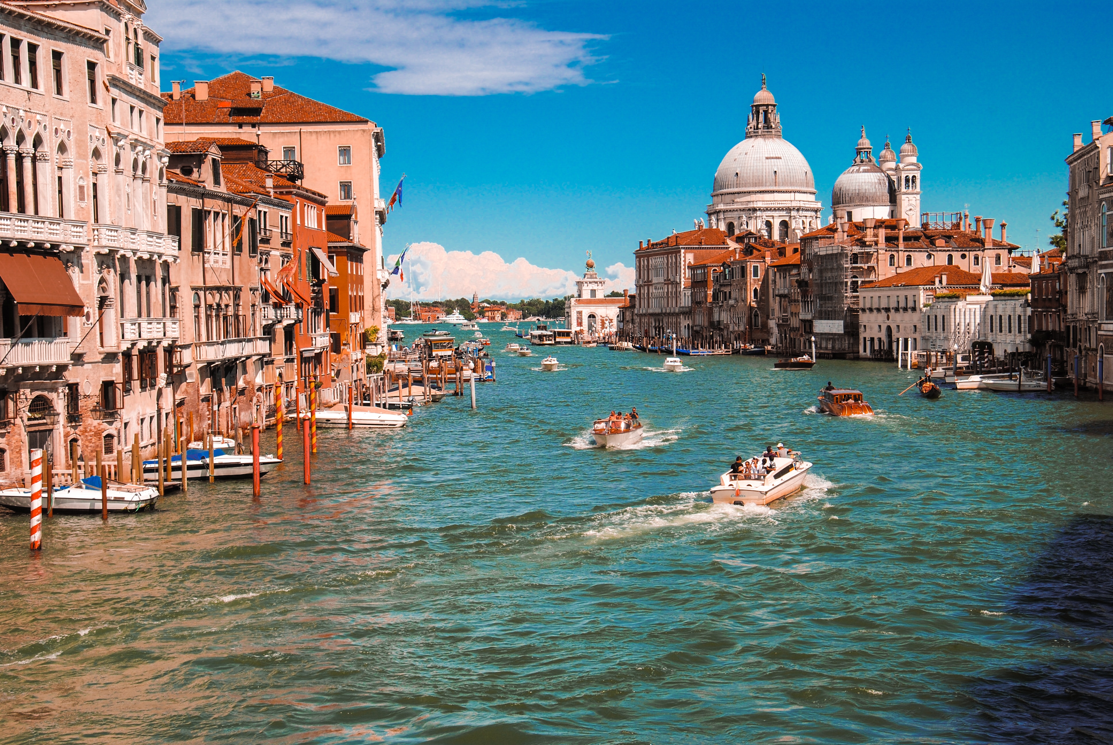 a water way with boats and buildings in the background with Grand Canal in the background