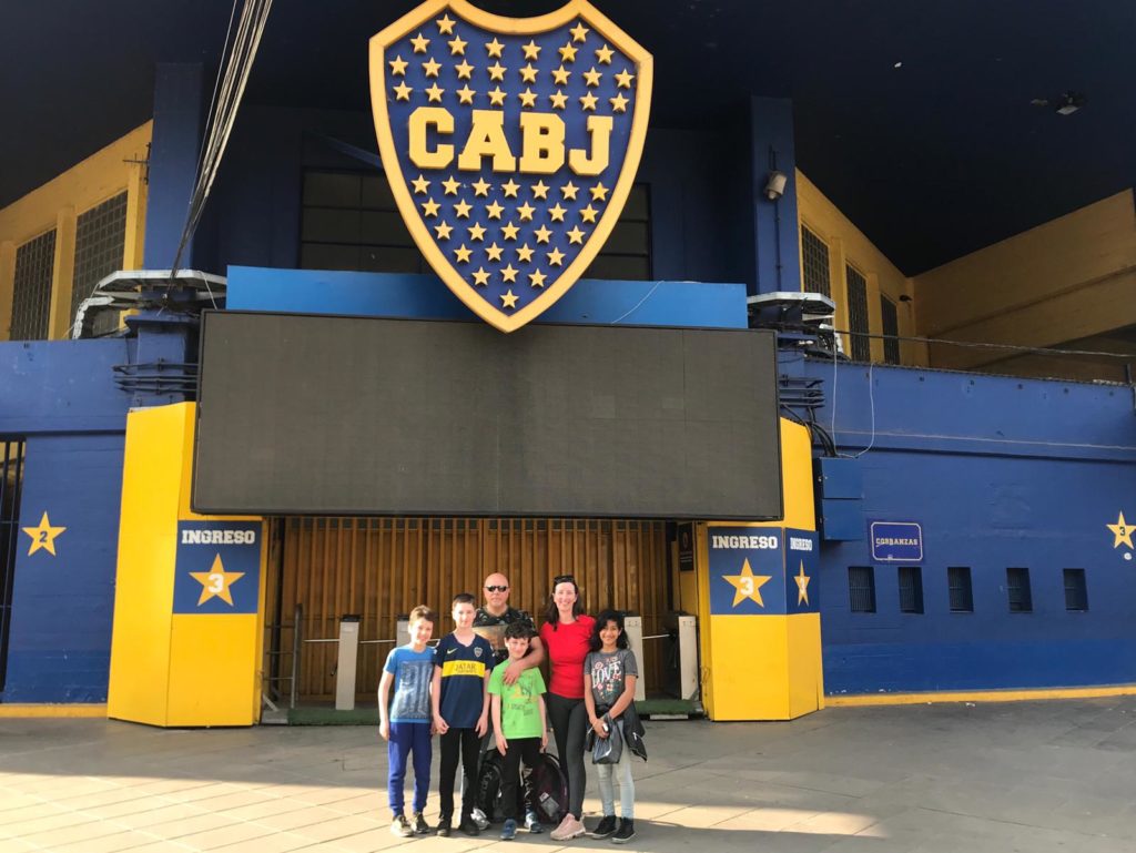 a group of people posing for a photo in front of a blue and yellow building