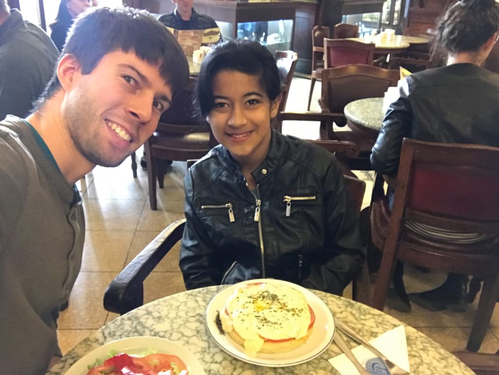 a man and woman sitting at a table with food