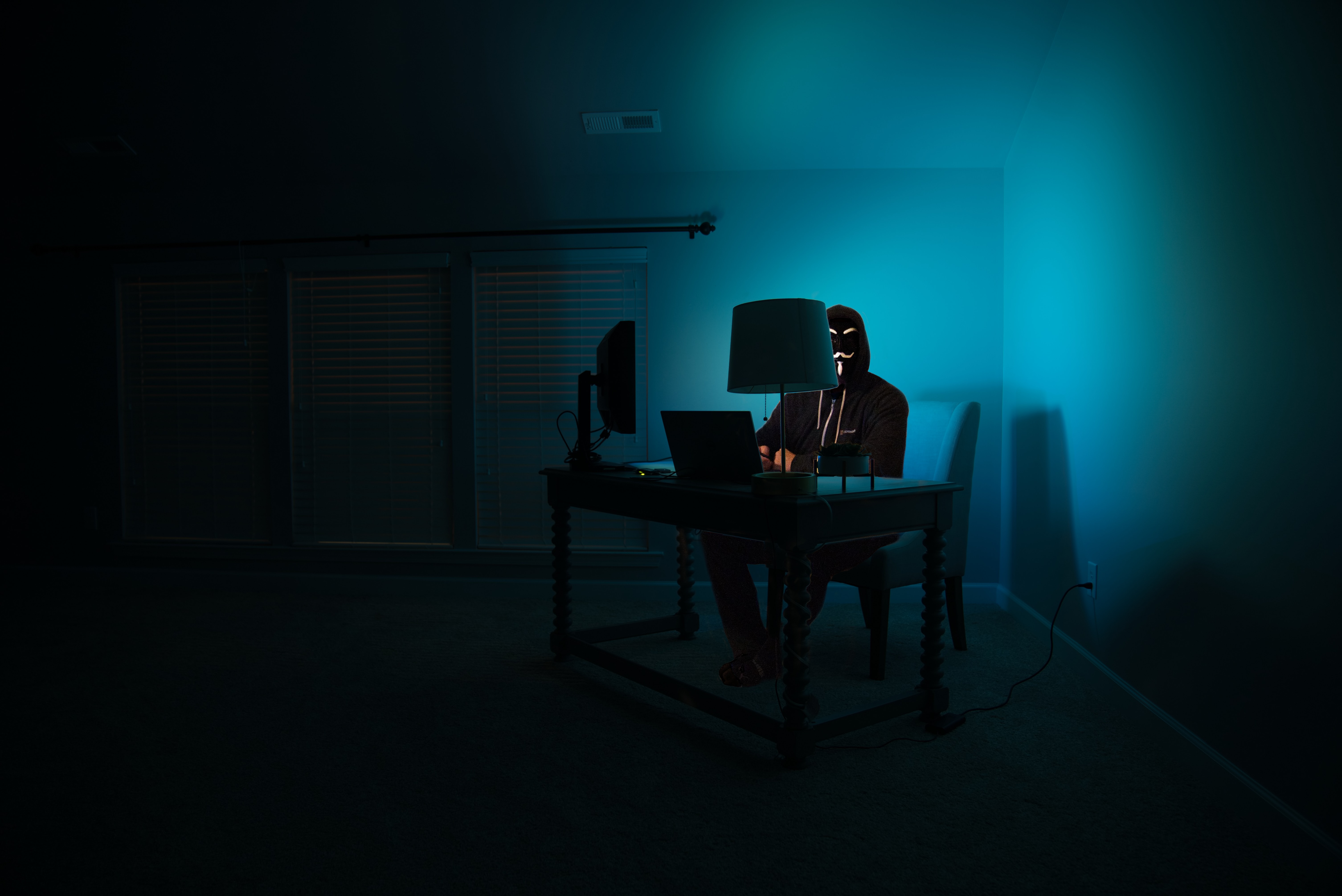 a person in a mask sitting at a desk with a computer