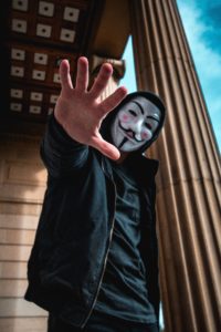 a man wearing a mask and holding his hand up