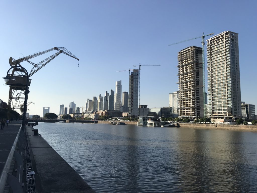 a body of water with cranes and buildings in the background