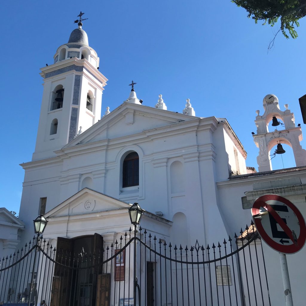 a white church with a gate and a sign