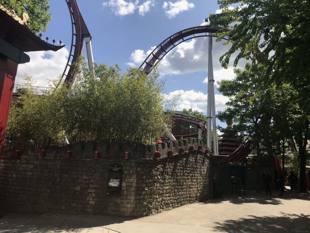 a roller coaster with trees and a stone wall