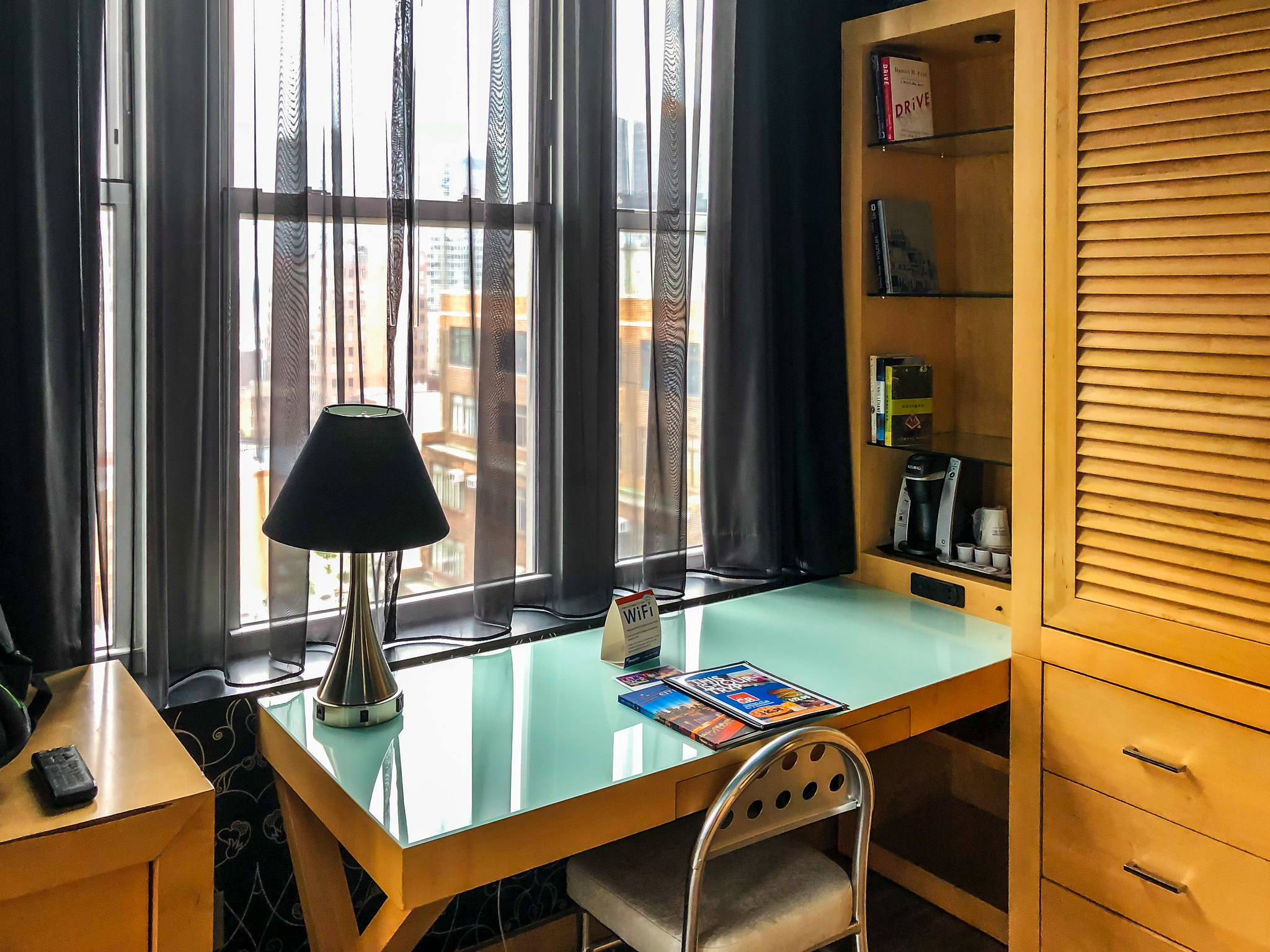 a desk with a lamp and a bookcase by a window