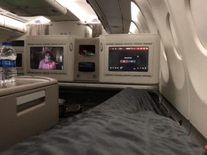 a bed with two screens on the side of the plane