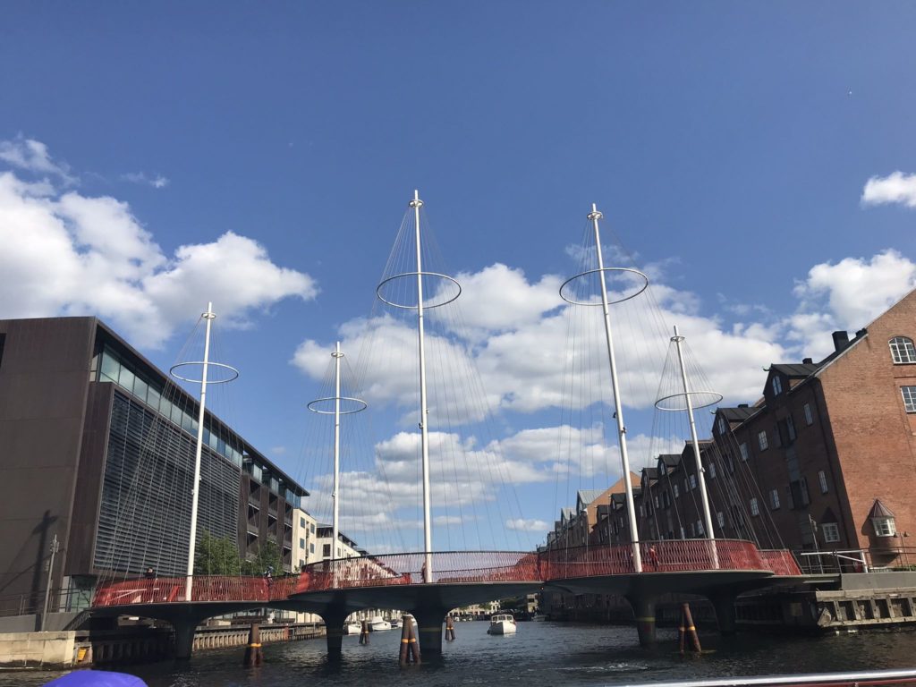 a bridge with white poles and red railings over water