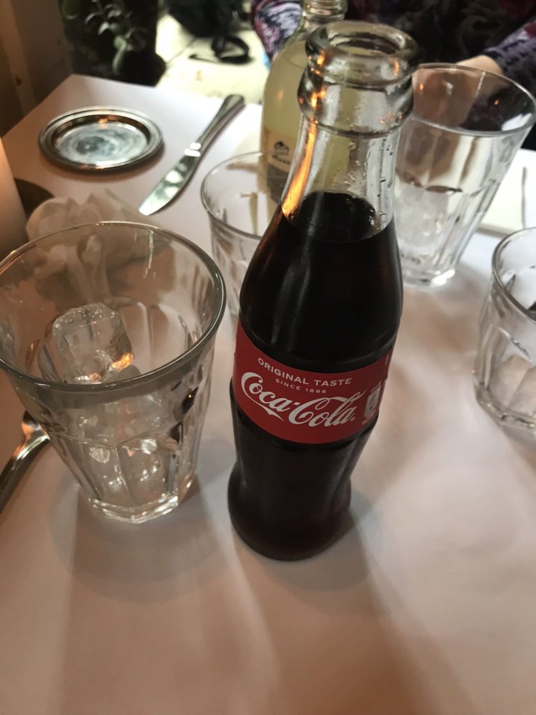 a bottle of soda and glasses on a table