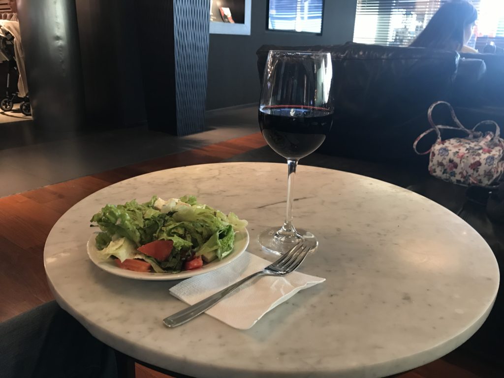 a glass of wine and a plate of salad on a table