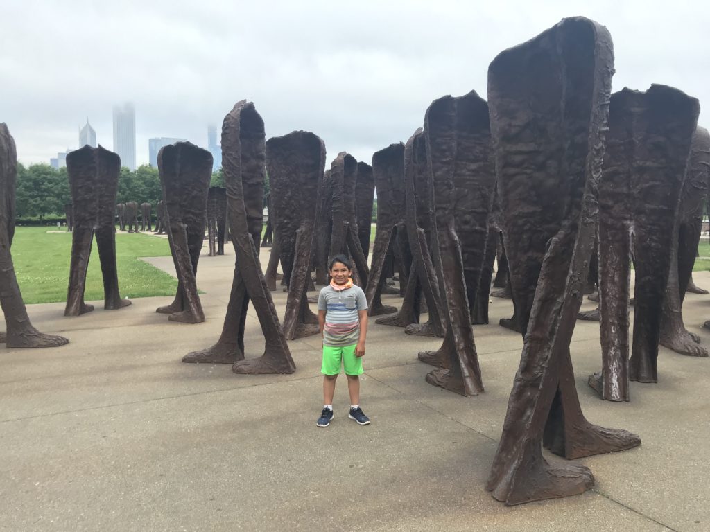 a boy standing in front of a group of sculptures