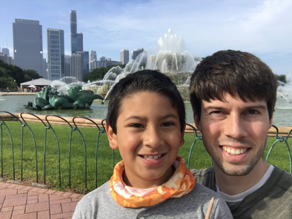 a man and boy taking a selfie in front of a fountain