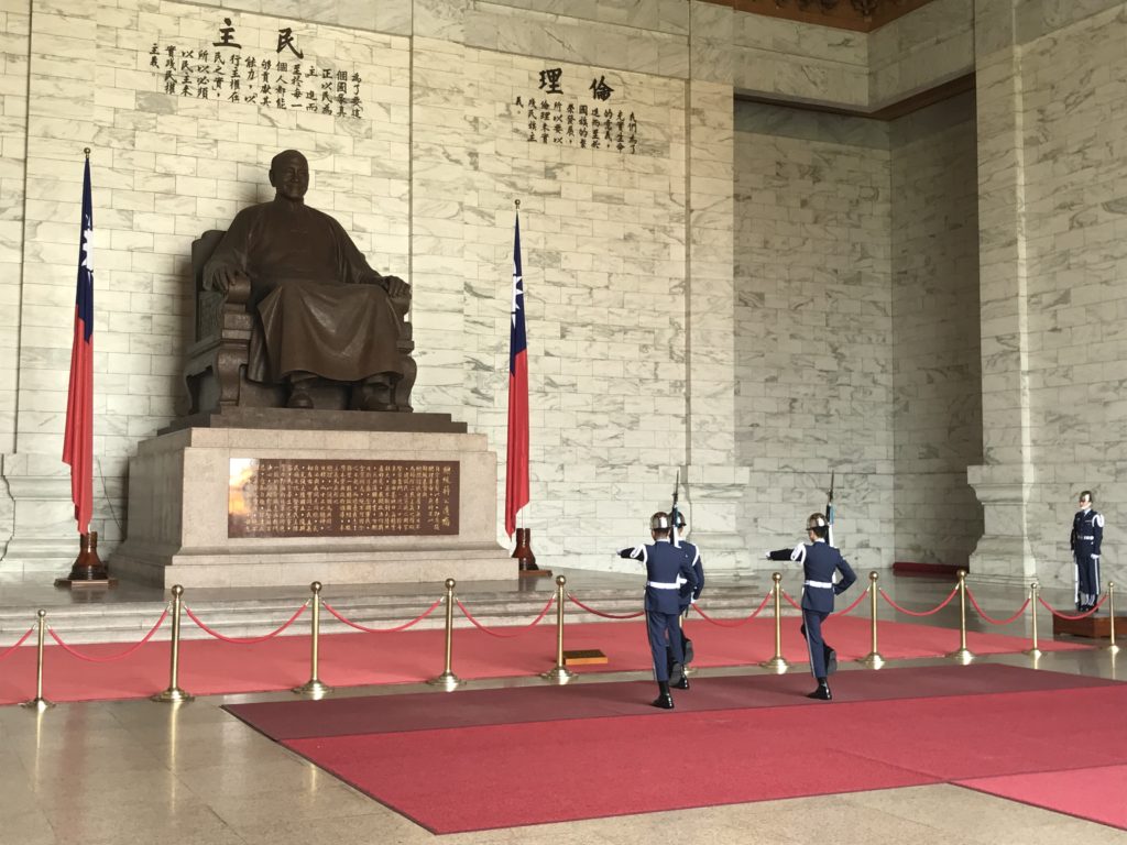 a group of people in uniform standing in front of a statue