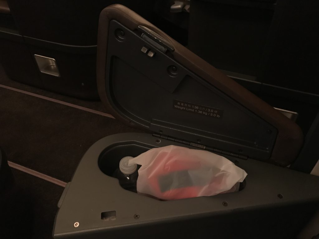 a plastic bottle in a plastic bag in a arm rest