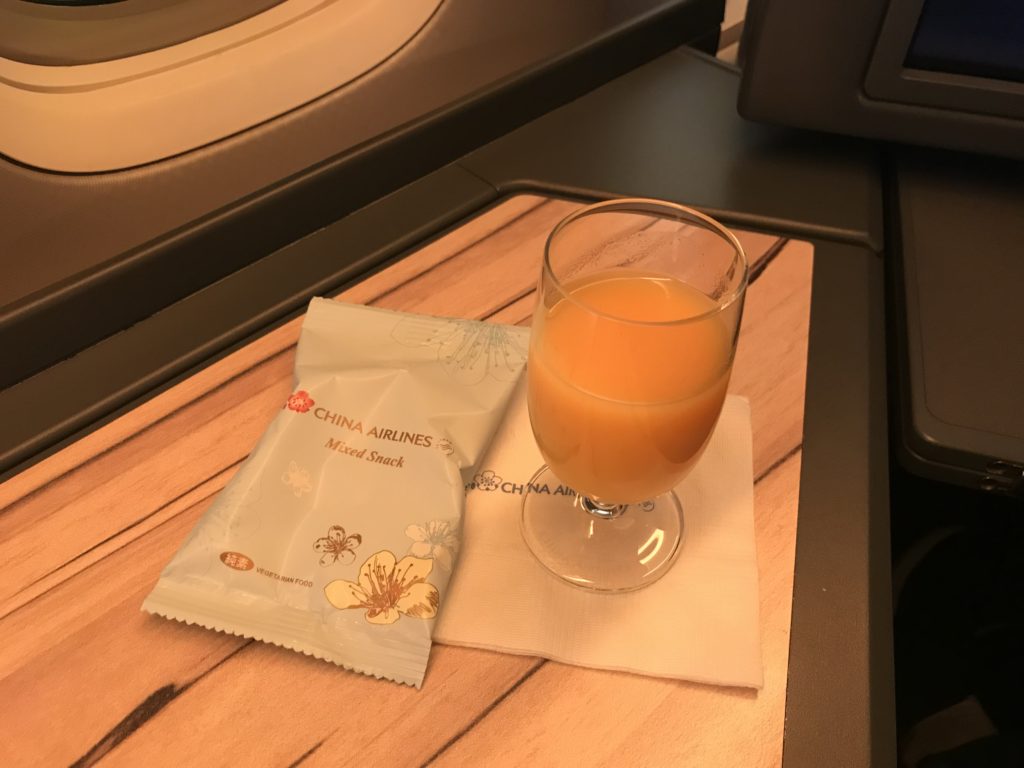 a glass of orange juice and a packet of food on a table