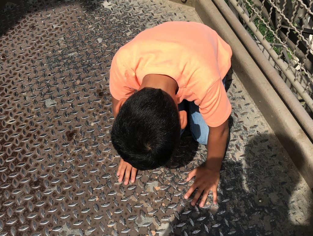a boy kneeling on a metal surface
