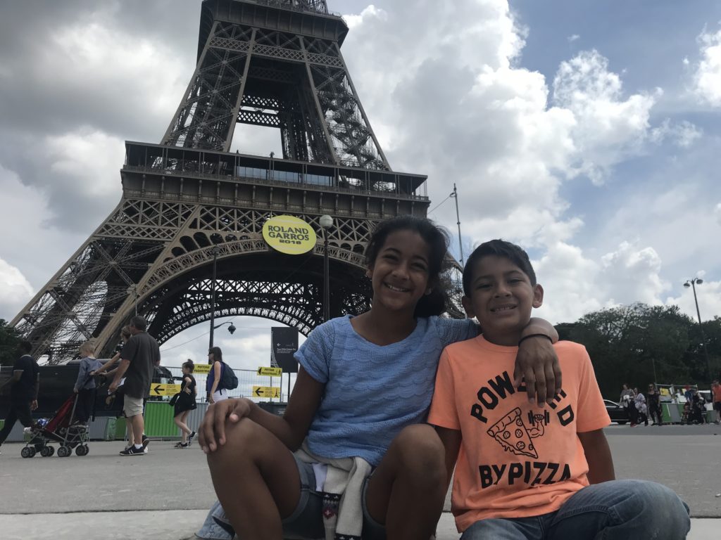 a couple of kids posing for a picture in front of a large metal tower