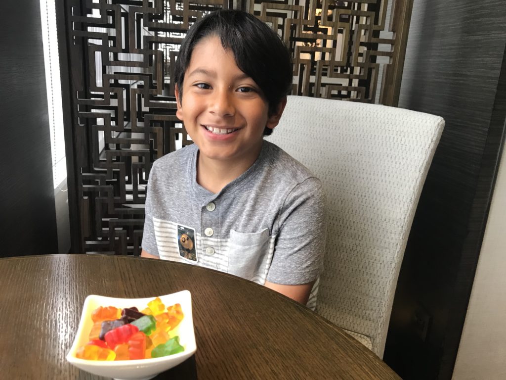 a boy sitting at a table with a bowl of gummy candies