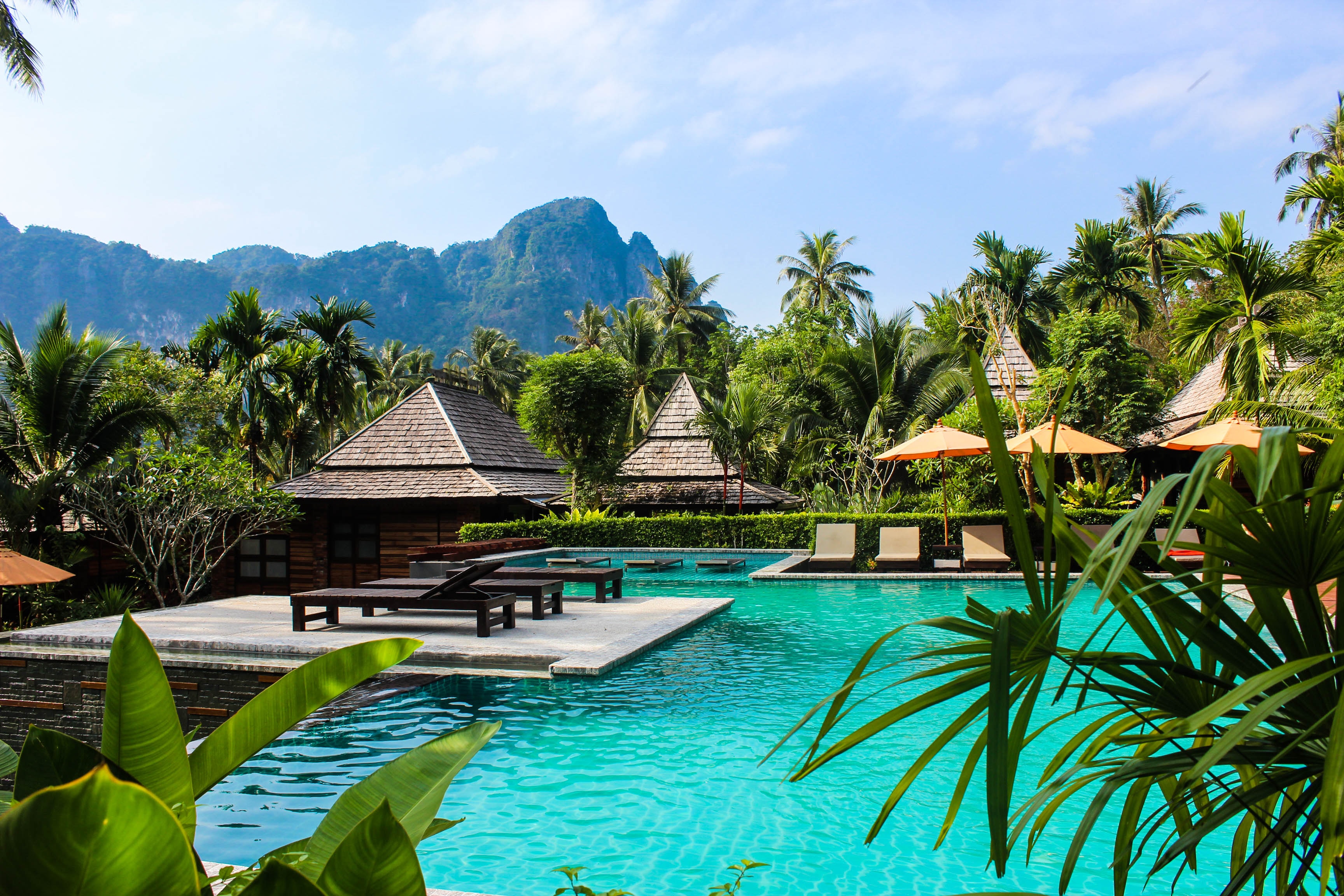 a pool with chairs and umbrellas in the middle of a tropical resort